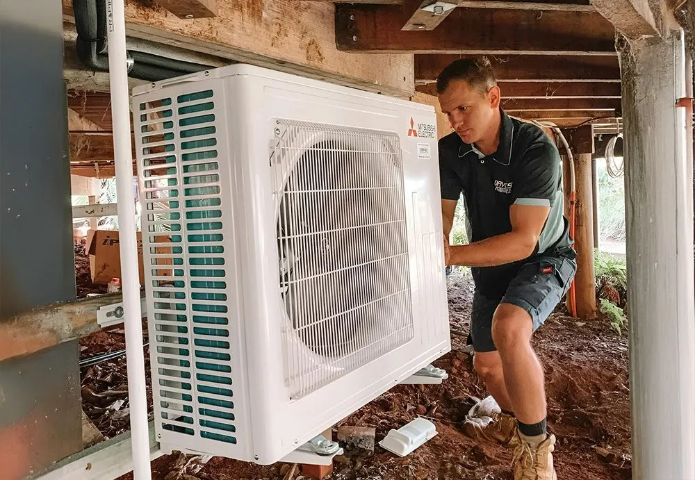 Davies technician installing an air conditioner under a house